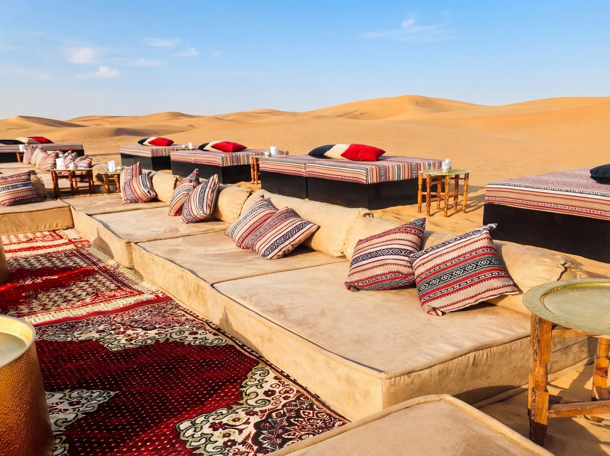 LOUNGE LOW SEATING on sand dunes with cushioned platforms, patterned pillows, and wooden side tables, creating an inviting, intimate gathering space.