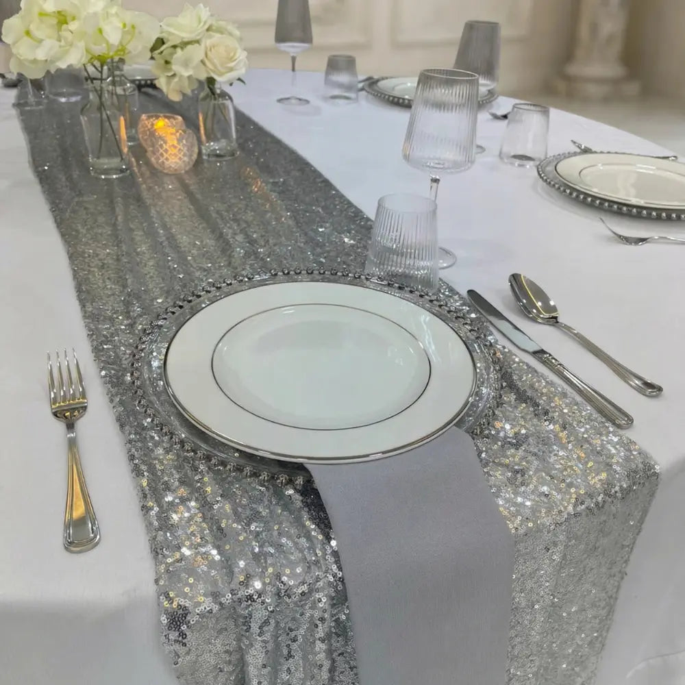Sequin Table Runners elegantly adorn a white tablecloth, with polished table settings and floral centerpieces, enhancing any special occasion&