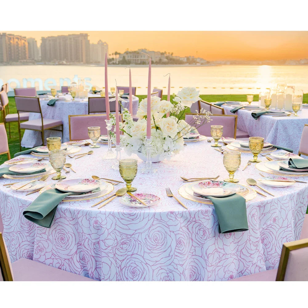 Pink Floral Round Tablecloth elegantly drapes a dinner party setup with glassware and a gold cup, enhancing event aesthetics with its premium linen feel.