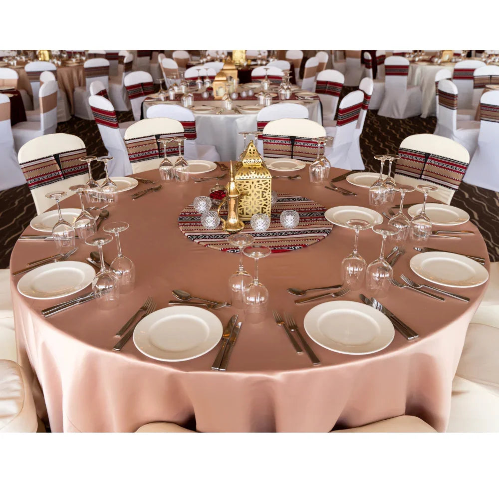 Round Tablecloth Satin on a dinner table set elegantly with tableware and wine glasses, ideal for special occasions.