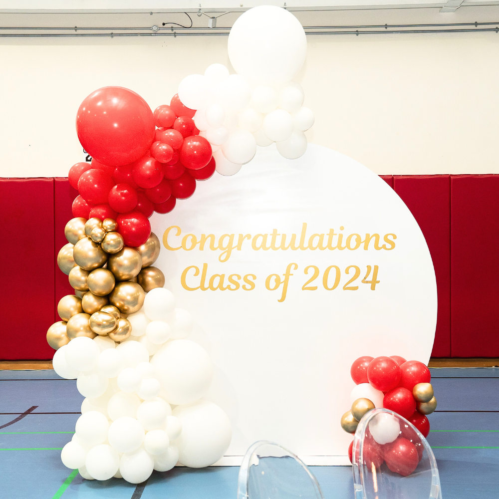 Round Wood Balloon Backdrop featuring a white and red balloon arch with gold text, perfect for enhancing any celebration with customizable balloon arrangements.
