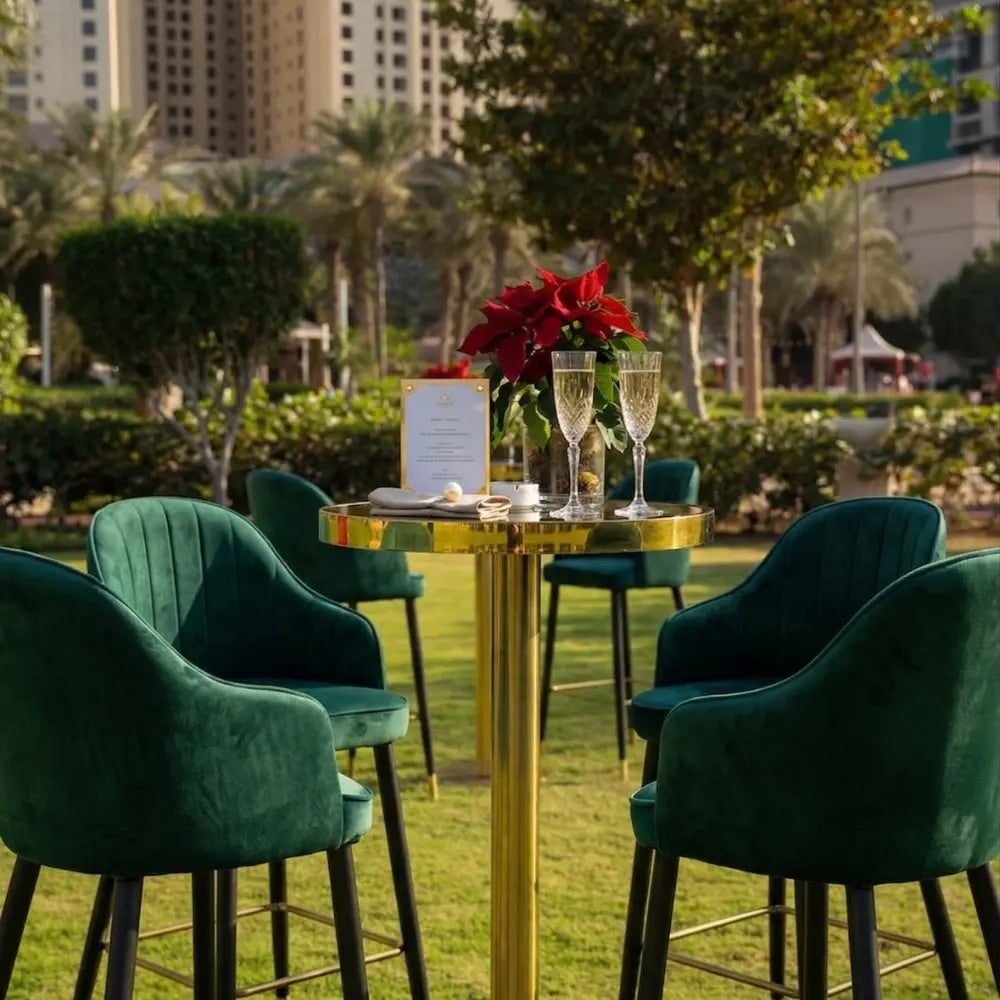 VELVET STOOL ROYAL GREEN set around a gold-tone bar table with elegant dining setup, perfect for stylish events in urban gardens.