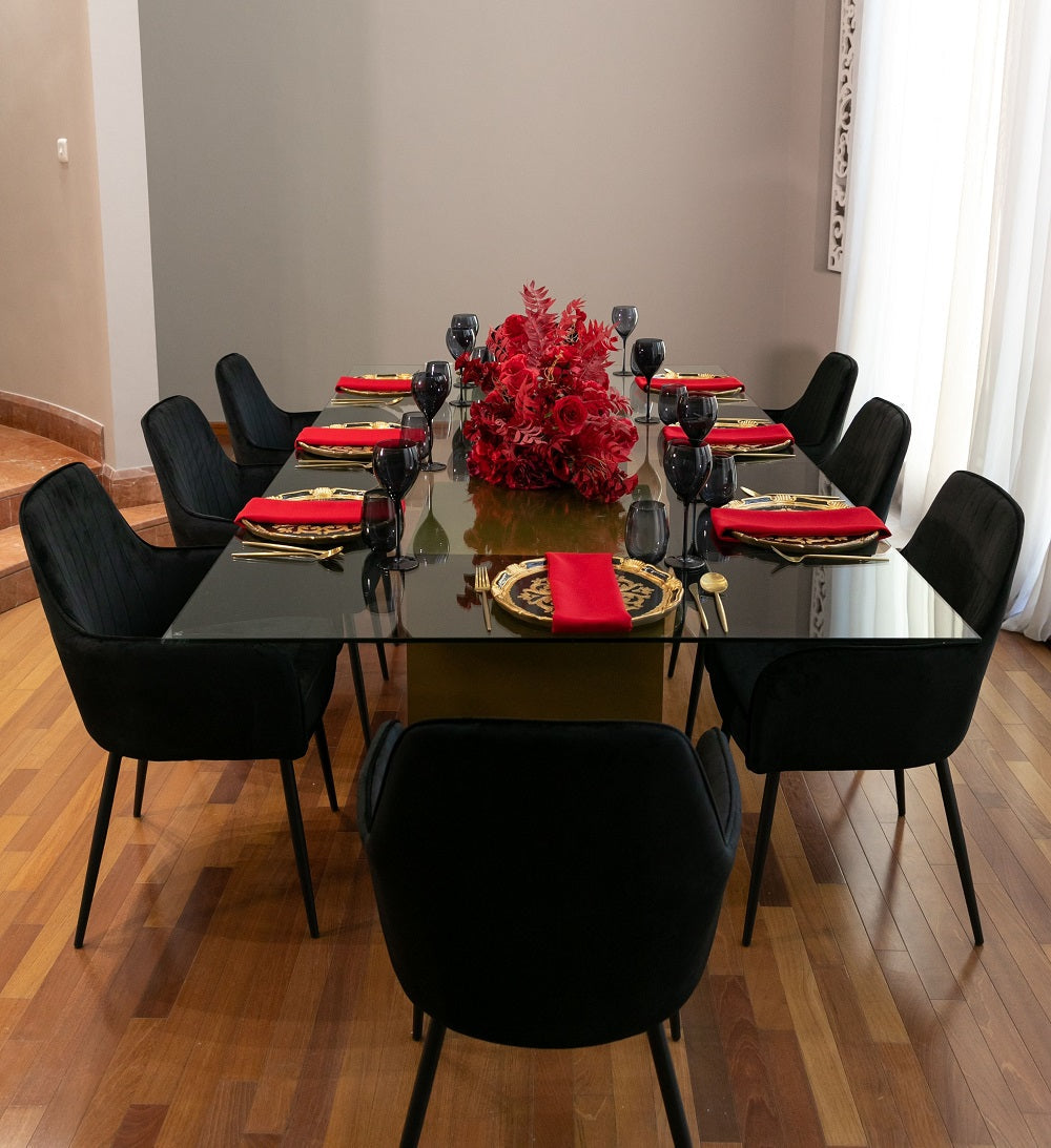 VELVET CHAIR BLACK with elegant design, featuring black legs, suitable for weddings and corporate events, seen arranged around a dining table with red floral centerpiece.
