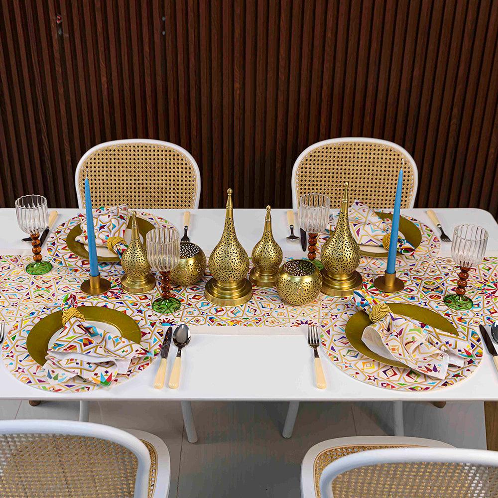 Elegant table setting with Arabesque Polyester Linen Placemat, gold and silverware, candles, and glassware.
