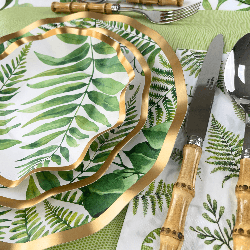 Fern & Foliage Paper Dinner Plate-8 Per Package displayed with utensils and plates. Elegant green fern design with gold foil trim. Perfect for events.