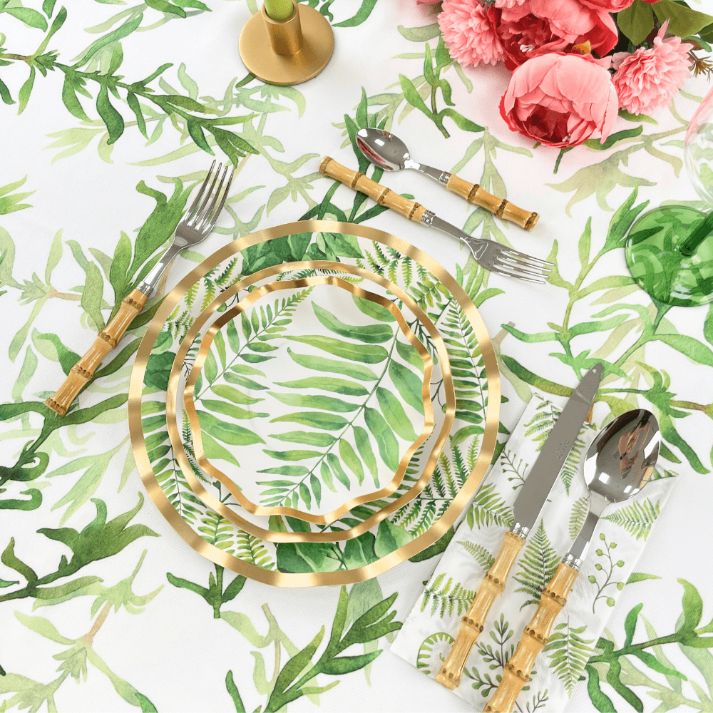 Fern & Foliage Paper Salad & Dessert Plate-8 Per Package displayed with silverware and flowers on a table. Elegant gold foil trim enhances the ruffled edge plates, perfect for events.