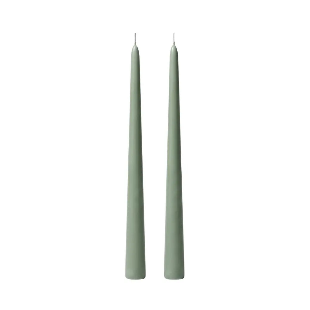 Two slim, pointed taper candles in a muted sage green color, standing upright side-by-side on a plain white background.