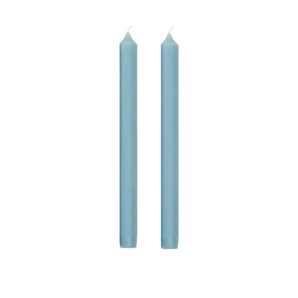 Two tall, slender light blue taper candles standing upright side by side on a plain white background.