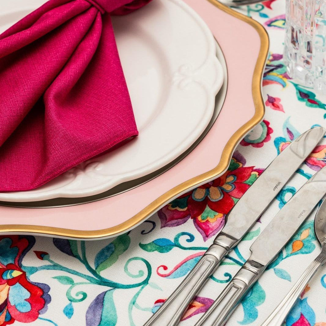 A folded napkin on a plate, accompanied by silverware on a table.