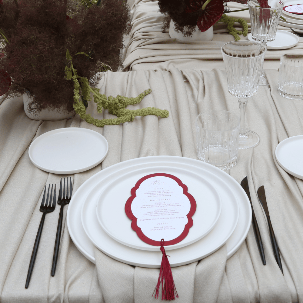CERAMIC PLATES - WHITE elegantly arranged on a formal table setting with black-handled cutlery, glassware, and floral décor, ideal for weddings or special events.