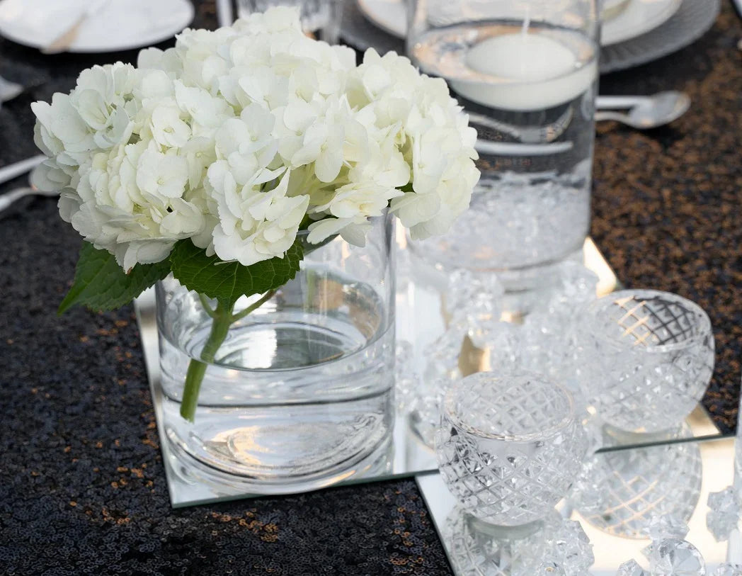 Crystal Tea Light Candle Holder, 6cm H x 6.5cm Dia, with flowers and candles on a table. Enhance your event with this elegant centerpiece. Candles sold separately. Tableware from Party Social Dubai.
