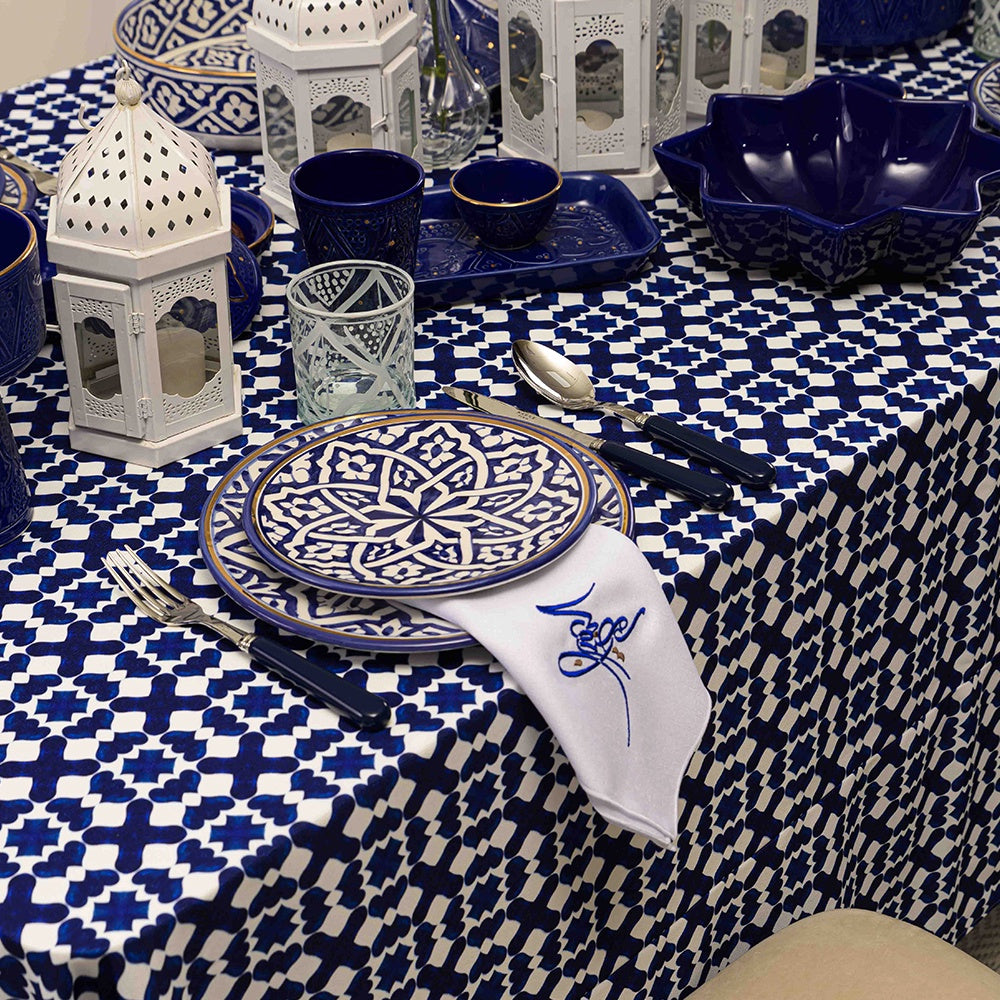 Table setting with plates, utensils, bowl, cup, glass, and napkin on Marrakesh Patterned Polyester Linen Tablecloth.