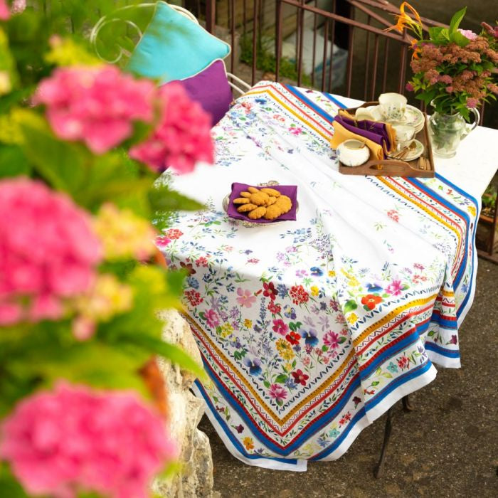 Vibrant Primrose Pure Linen Tablecloth adorned with floral decor and cookies on a table.