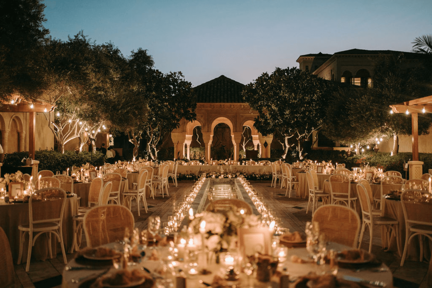 A romantic wedding reception at night, adorned with flickering candles and elegantly arranged chairs.