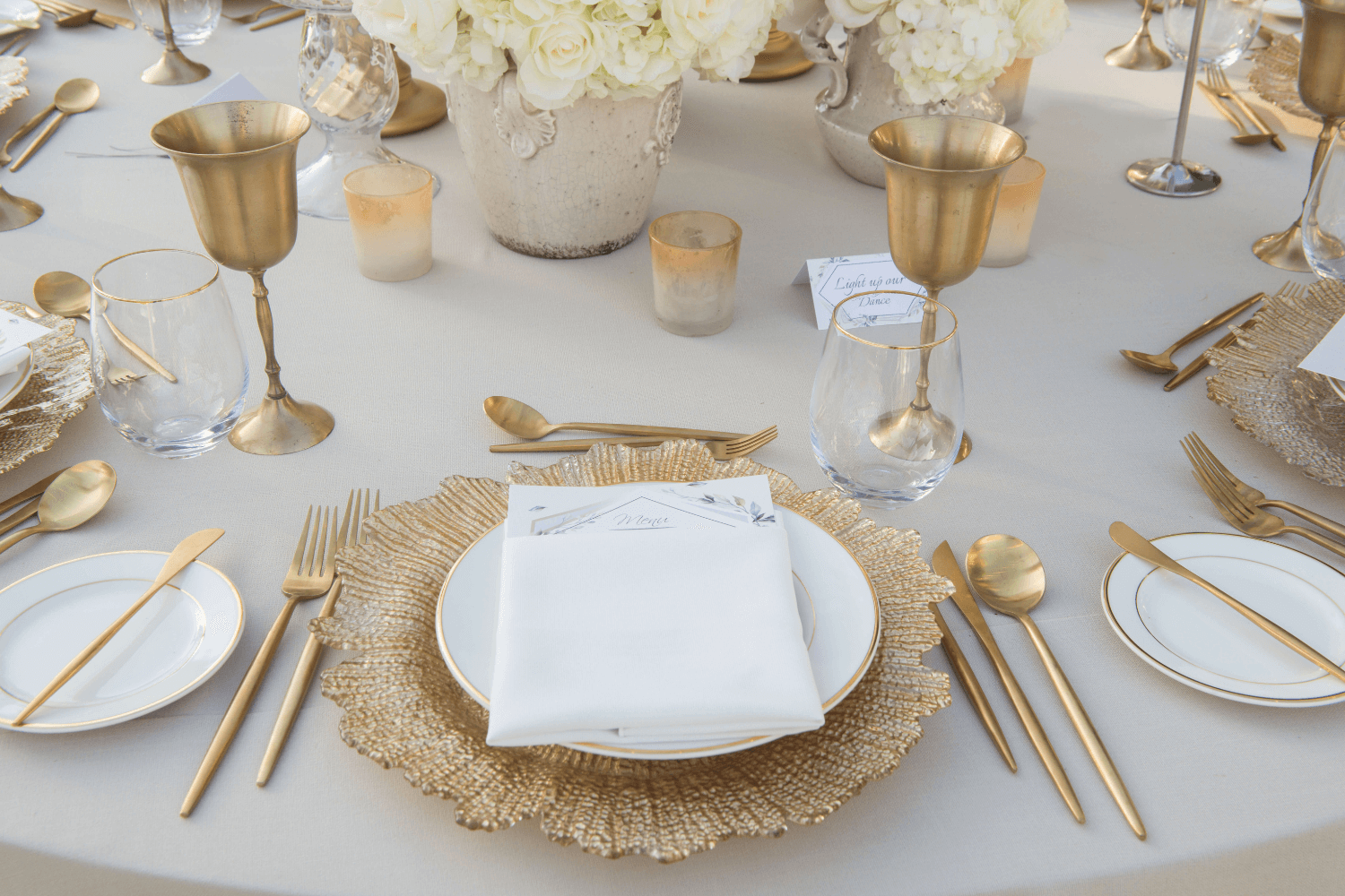 Elegant outdoor luxury wedding tablescape at The Address Montgomerie, styled with white floral centerpieces, gold accents, and crisp table linens under soft natural lighting.