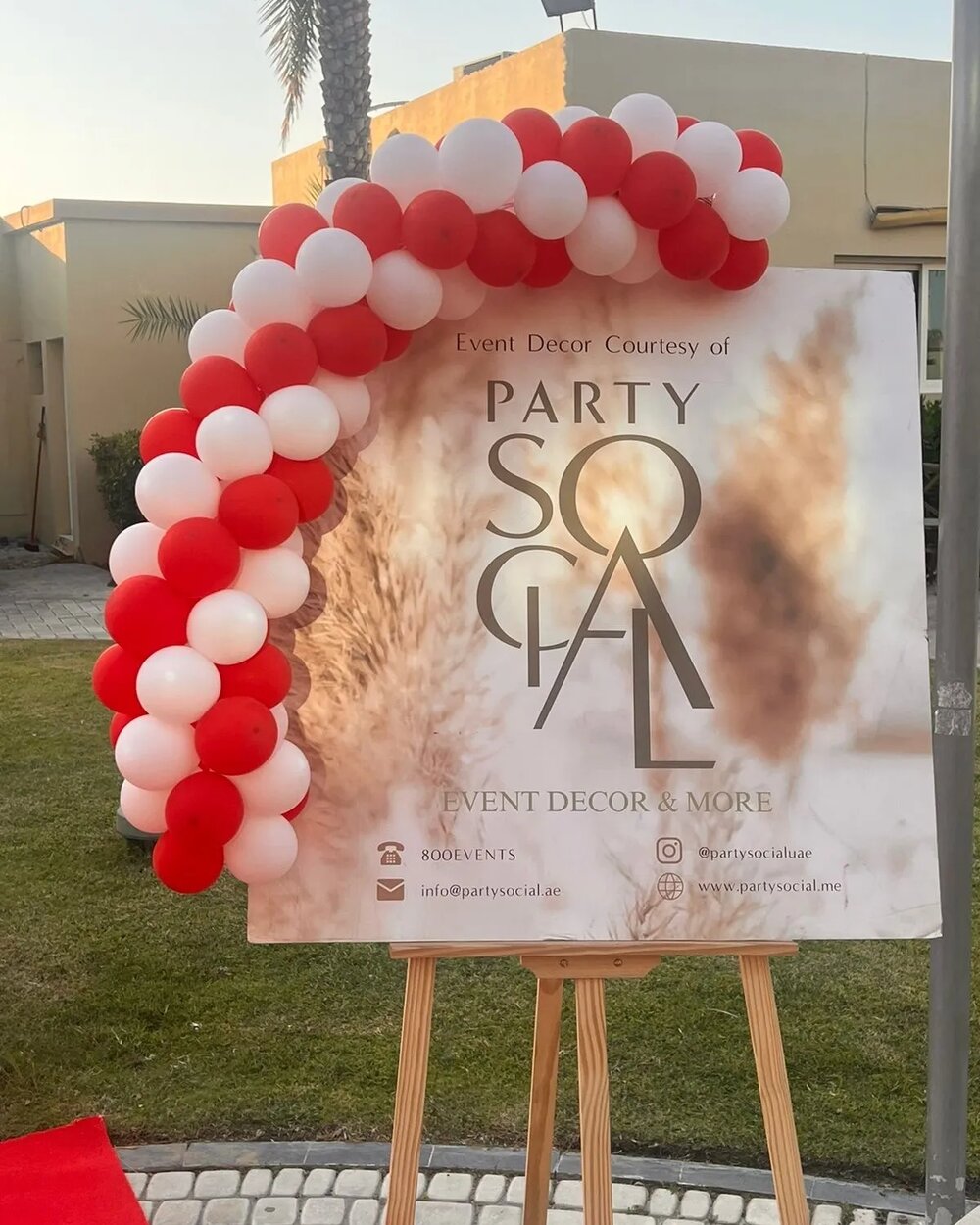 Red and white balloons in an arch on a sign. 