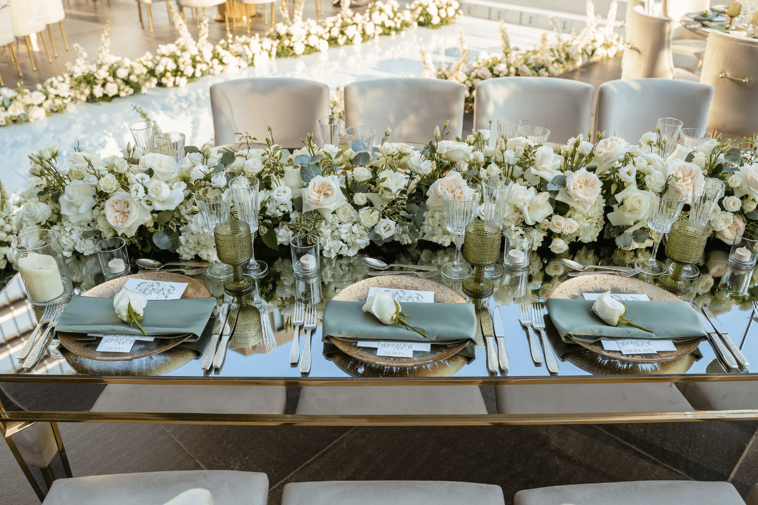 A beautifully arranged table featuring white flowers and elegant gold place settings, designed by Party Social Dubai.