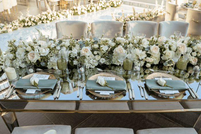 A beautifully arranged table featuring white flowers and elegant gold place settings, designed by Party Social Dubai.
