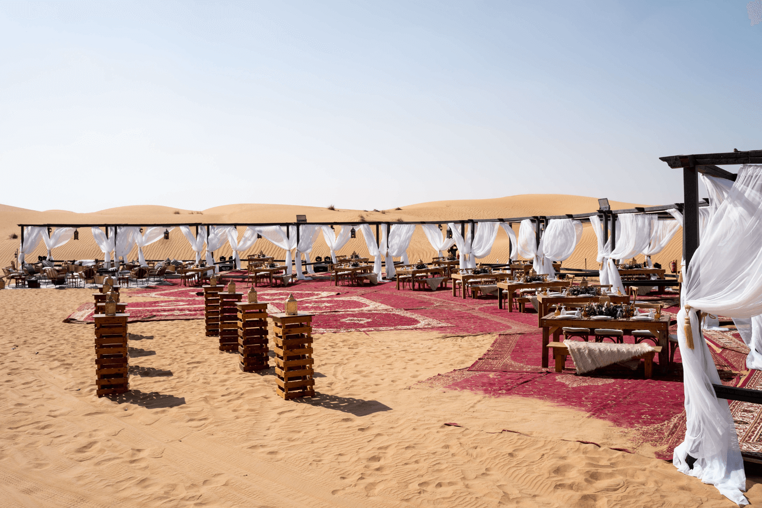 A desert dinner event in Dubai with beautiful seating and tablescapes under the clear blue sky.