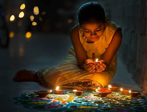 Woman decorating a rangoli with diyas for Diwali