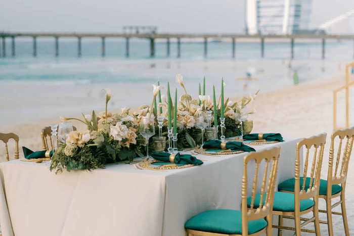 A beautifully arranged wedding table on the beach, adorned with elegant decor, by Party Social Dubai.