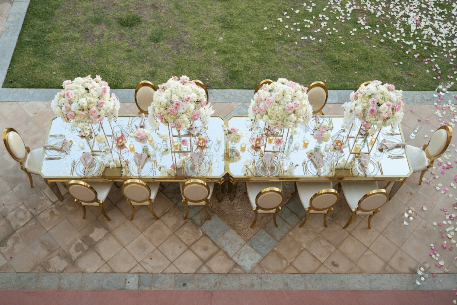 Elegant table setting with white and gold chairs adorned with fresh flowers.