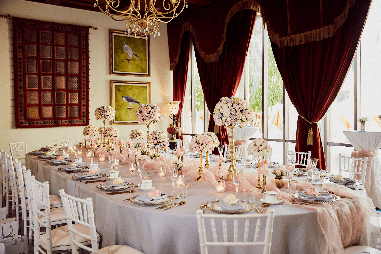 A long table adorned with white chairs and vibrant pink flowers, elegantly set for an event by Party Social Dubai.