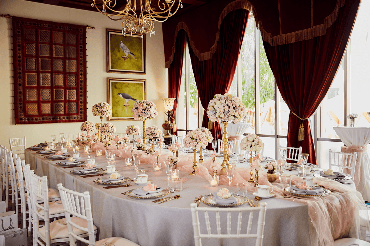 A long table adorned with white chairs and vibrant pink flowers, elegantly set for an event by Party Social Dubai.