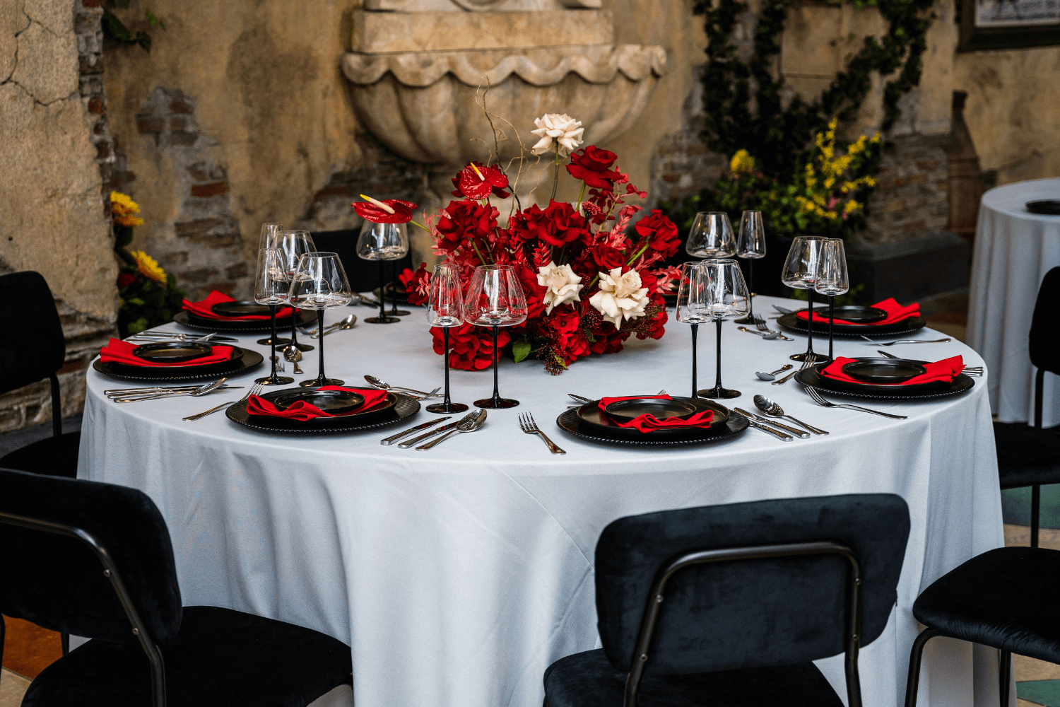 A table with black chairs and red and white flowers, provided by Party Social Event Rentals Dubai.