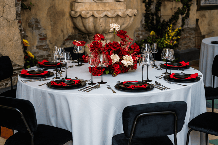 A table with black chairs and red and white flowers, provided by Party Social Event Rentals Dubai.