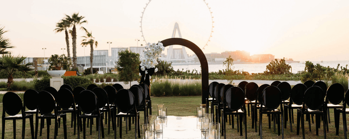 Elegant black and white wedding ceremony setup featuring black arch and black ghost chair furniture rentals by Party Social Event Rentals Dubai