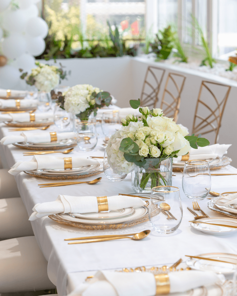 a table setup for a baby shower in shades of white and gold