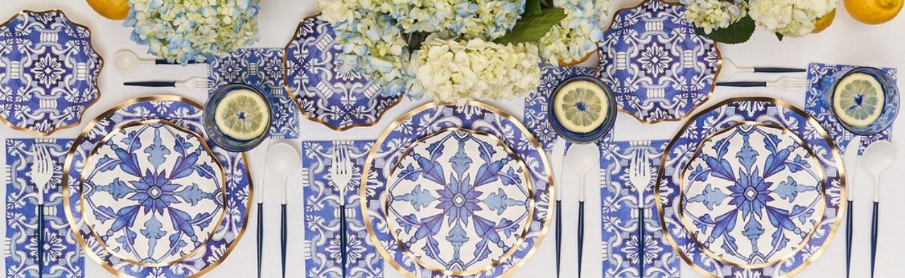 A table set with blue and white plates, flowers, candlesticks, and lemon slices, showcasing elegant party tableware.