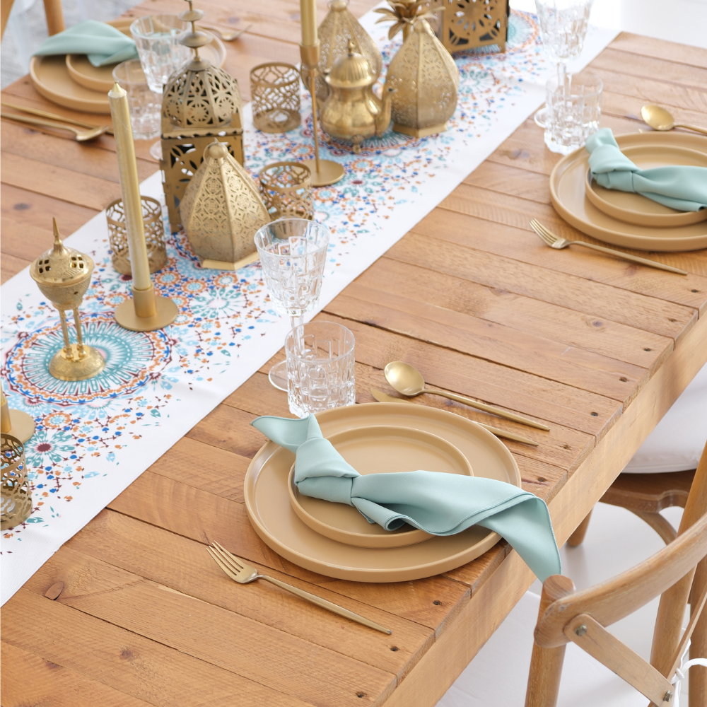 Golden Hour Iftar-Dining Setup featuring a wooden table with mosaic runner, brass lanterns, gold cutlery, ceramic plates, crystal glasses, and teal napkins for eight guests.