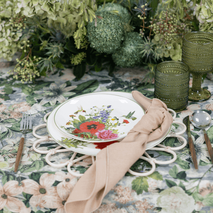 Garden Bliss- Dining Setup featuring a plate with floral design, gold cutlery, a green candle holder, and a glass on a table.