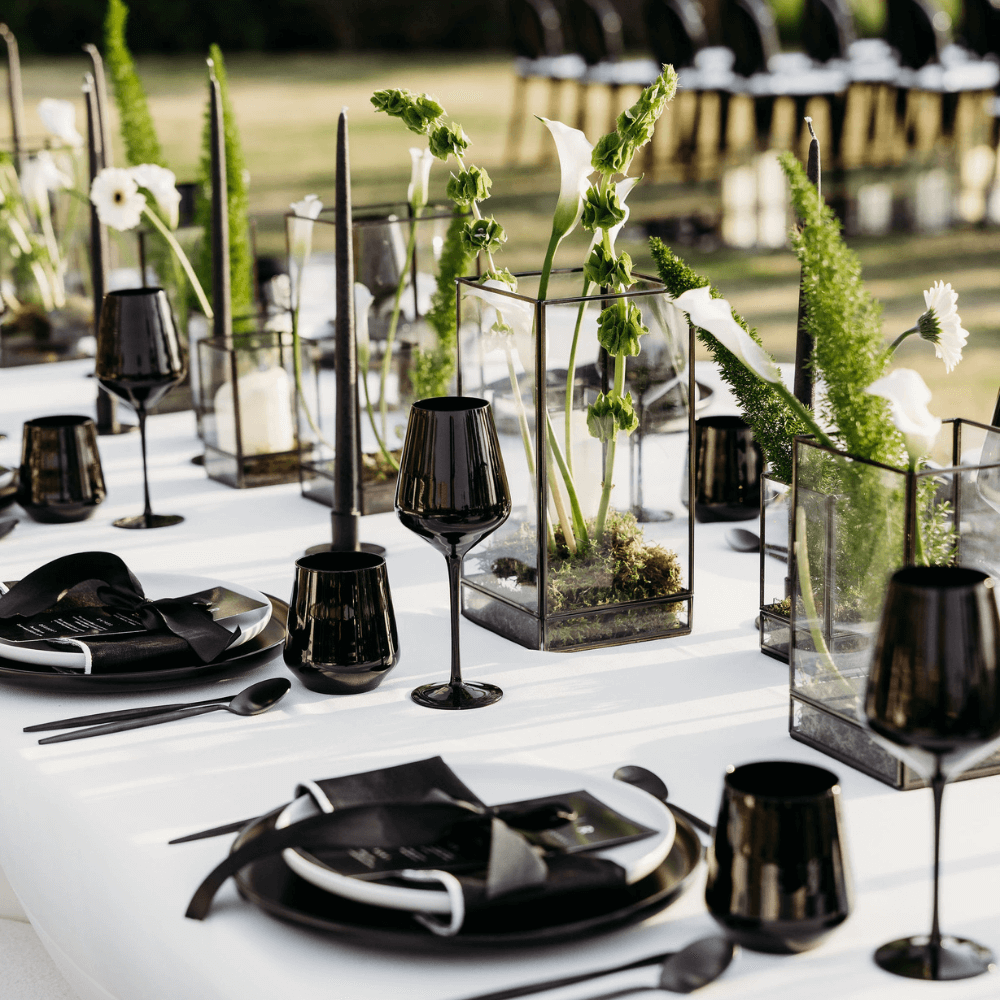 Monochromatic-Dining Setup featuring black and white tableware, wine glasses, and vases, elegantly arranged for eight guests, ideal for stylish events.