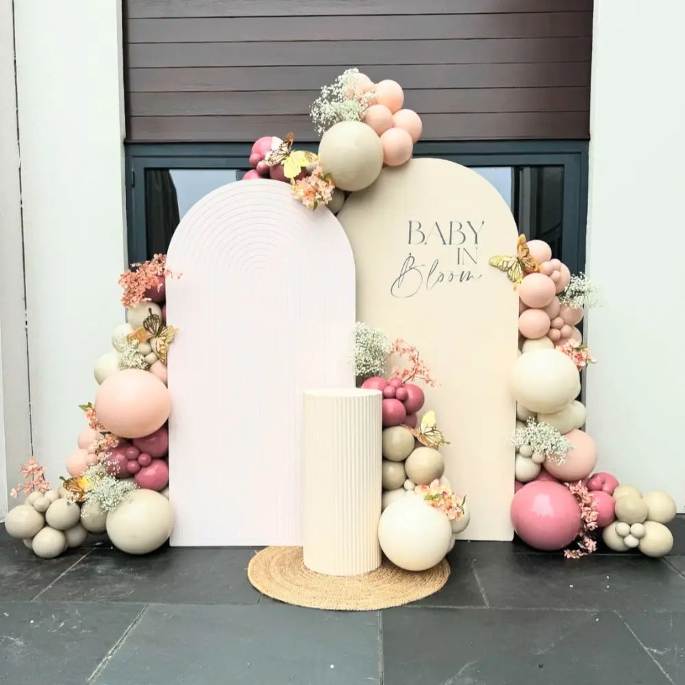 Blooming Elegance Backdrop featuring arched panels with balloon garland, floral accents, and a cylindrical podium, perfect for baby showers and events.