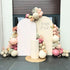 Blooming Elegance Backdrop featuring arched panels with balloon garland, floral accents, and a cylindrical podium, perfect for baby showers and events.