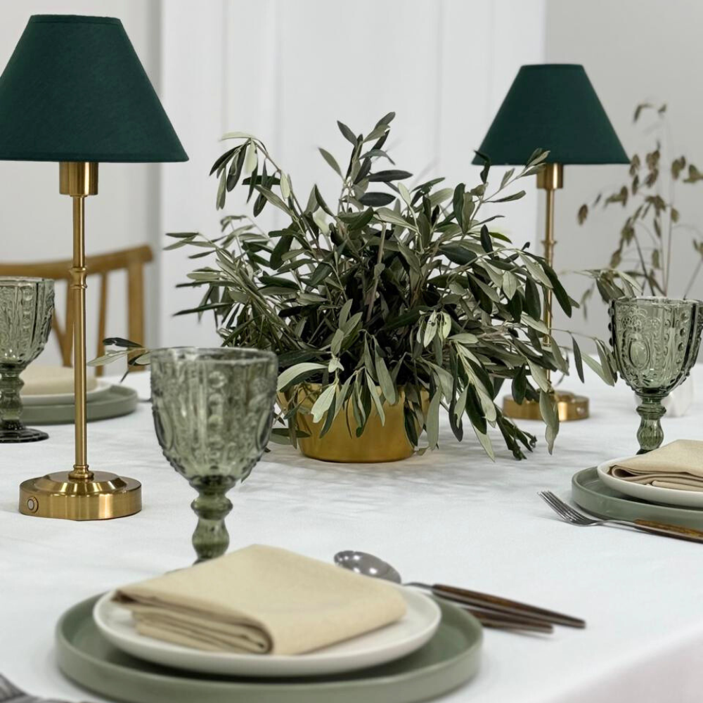 Serene Green-Dining Setup: Elegant table setting with plates, glasses, wooden cutlery, napkins, and a plant centerpiece, ideal for hosting 8 guests.