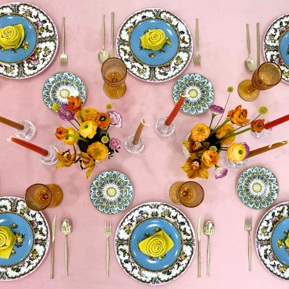 Blush Velvet Dreams-Dining Setup featuring a table with plates, napkin folded as a rose, flower centerpieces, candle holders, and goblets for an elegant party setting.