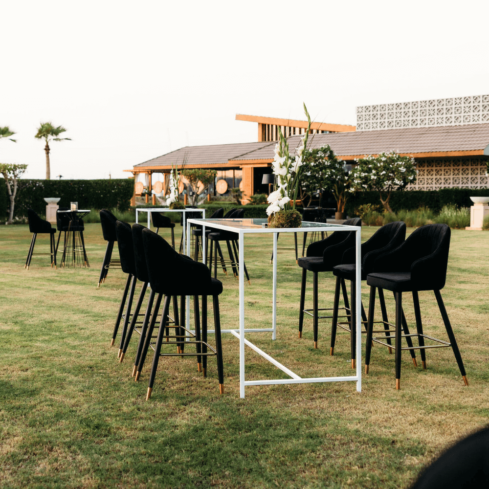 Monochromatic-Cocktail Setup: Outdoor arrangement featuring a table with eight black stools and a flower centerpiece, designed for hosting eight guests.
