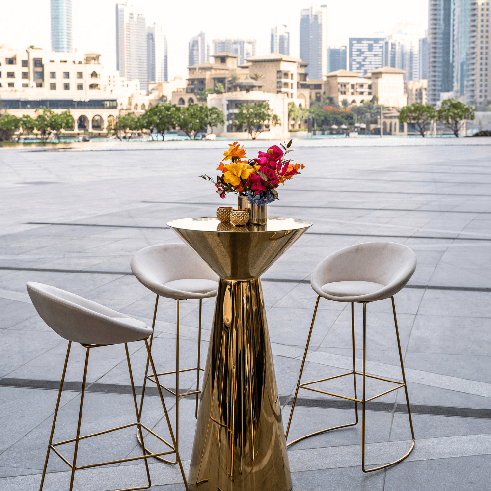 Golden Glam- Cocktail Setup: Elegant table with gold frame and white chairs, featuring a floral centerpiece, designed for eight guests, ideal for stylish events.