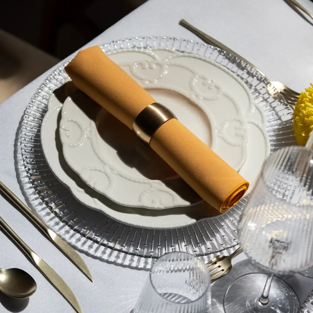CHARGER PLATE- CLEAR RADIAL GOLD elegantly set with dinnerware, mustard napkin, and gold flatware, perfect for sophisticated event settings by Party Social.