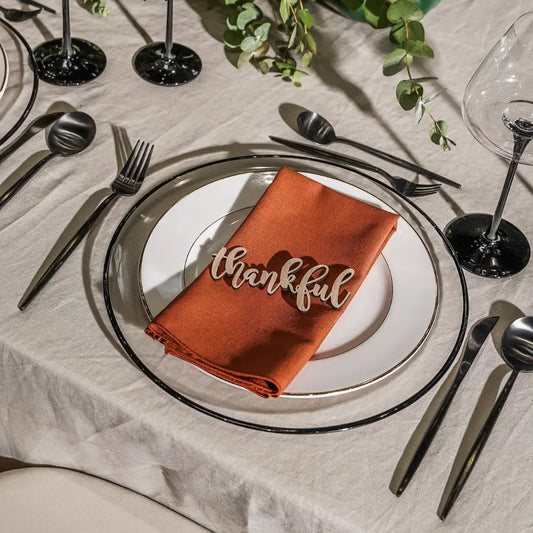 Clear Plate W/Black Rim Collection showcased in an elegant autumnal table setting with burnt-orange napkin and black flatware, ideal for sophisticated gatherings.