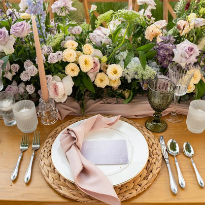 CANE PLACEMAT on a wooden table set for a special event, with elegant dinnerware, blush-pink napkin, floral runner, polished silverware, and vintage glassware.
