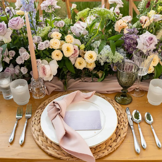 CANE PLACEMAT on a wooden table set for a special event, with elegant dinnerware, blush-pink napkin, floral runner, polished silverware, and vintage glassware.