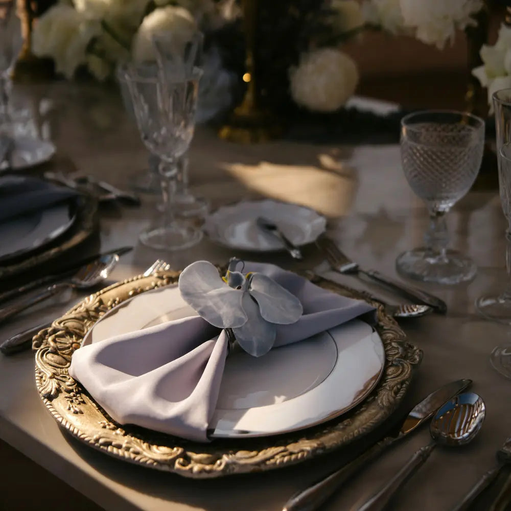 CHARGER PLATE - FLORENTINE ANTIQUE WOOD featured in an elegant table setting with silver utensils, crystal glasses, and a folded napkin with an orchid.