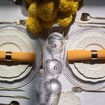 CHARGER PLATE- CLEAR RADIAL GOLD elegantly set on a table with embossed dinnerware, gold flatware, yellow napkins, and a vibrant yellow floral centerpiece.