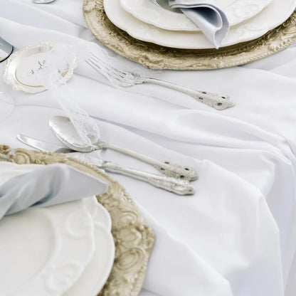 Close-up of CUTLERY VINTAGE SILVER (SET OF 4 PIECE) elegantly arranged on a formal table with ornate plates and a decorative place card.