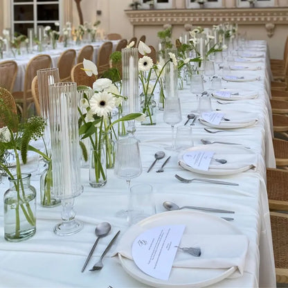 Elegant reception table featuring CERAMIC PLATES - WHITE, set with folded napkins, floral runner, glassware, and cutlery, perfect for weddings or formal events.